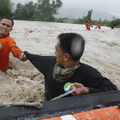 A Philippine Coastguard rescuer helps a colleague while crossing a flooded area with strong current in Botolan town in northern Philippines August 7, 2009. (REUTERS/Erik de Castro)