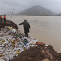 A man walks on sandbags used to patch a damaged dike holding back a rising river in a flooded village in Cangnan county, eastern China Sunday Aug. 9, 2009. (AP Photo)