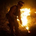 Firefighters from the Orange County Fire department work a 3800 acre brush fire near Irvine, Calif., Sunday, Oct. 21, 2007. 
10/21 星期日，橙縣消防隊員在靠近爾灣市正在燃燒的灌木火叢旁