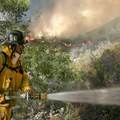 A firefighter douses a hot spot as flames descend a ridge behind him in Live Oak Canyon in eastern Orange County, Wednesday, Oct. 24, 2007. 
2007/10/24 星期三，桔縣火場漫延過另外一個山谷。