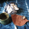 小茶杯是拉坏拙作，布杯墊是逛精品店時買的，外出時為了攜帶方便，所以利用舊衣縫製一個「阿信袋」收納茶杯和杯墊。