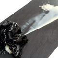 「墨魚燉飯」展現江振誠調皮的一面，顛倒傳統，白色是剁碎的墨魚、黑色是烤成的蔬菜燉飯片，應驗「眼見非為真」的美食哲學。