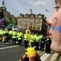 A woman blows bubbles in front of a line of police officers in the centre of Glasgow during a protest against climate change and the M74 road extension July 8, 2005. REUTERS/Jeff J Mitchell