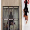 An acrobat drops past onlookers in an office window on a building in the landmark Rockefeller Center during the 'Target Vertical Fashion Show' in New York, July 27, 2005.  REUTERS/Mike Segar