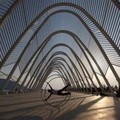 A street theater artist performs at the Olympic complex of Athens as the Olympic velodrome is seen in the background on Tuesday, Aug. 2, 2005. (AP Photo/Thanassis Stavrakis)