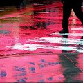 The lights from a Times Square billboard are reflected on the wet pavement on Broadway as a pedestrian crosses the street. (AFP/Timothy Clary)