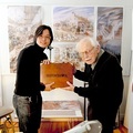 堤大介（左）與弗烈德瑞克・貝克，他們手中的木箱裡裝著《旅行的繪本》
