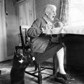 Old lady eats her dinner alone whilst her cat paws her and waits to be fed with scraps and titbits from her plate - by Andy Palmer, UK