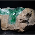 這塊翠玉璞已被切開一塊,
可以見到粗糙圍岩裡包裹著鮮豔的翠玉.
緬甸北部所產的輝玉, 含鉻, 鐵等元素的離子,
呈現翠綠與褐紅, 俗稱鮮豔的輝玉為翡翠.